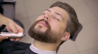 Rastalı berber sakallı adamı tıraş eder. Berber dükkanında sakal buduyorum. Yakışıklı müşteriler için sakal ve bıyık kesiyorum..