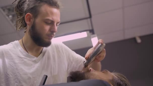 Friseur Mit Dreadlocks Rasiert Einen Bärtigen Mann Trimmen Bart Friseursalon — Stockvideo