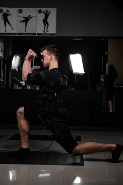 Spor salonunda EMS giysisiyle fiziksel egzersiz yapıyor. Elektrik kas stimülasyonu giysisinde spor eğitimi.