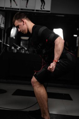 Spor salonunda EMS giysisiyle fiziksel egzersiz yapıyor. Elektrik kas stimülasyonu giysisinde spor eğitimi.