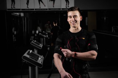 Spor salonunda kaslı bir antrenör elektrikli vücut giysisi giyerdi. Elbise üzerindeki kontaktörlerle elektro itici uyarma