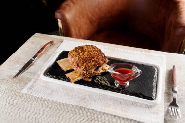 Barbekü kaburgaları, hardal taneleri ve siyah tahta tabakta sos..