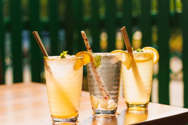 Limonlu kokteyller, bardakta nane şekeri ve bir restoranın arka planında ahşap bir masada duran tüp. Soğuk limonata.