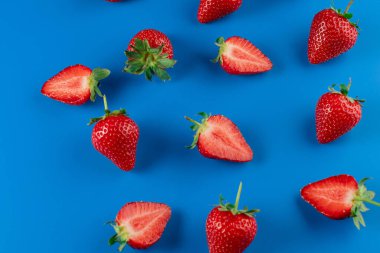 Mavi arka planda çilek dilimleri ve tüm çilekler. Mevsimlik çilek