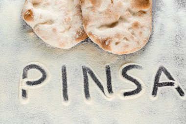 Dough and flour with text pinsa on black background. Pinsa romana and scrocchiarella gourmet italian cuisine. Traditional dish in italy clipart