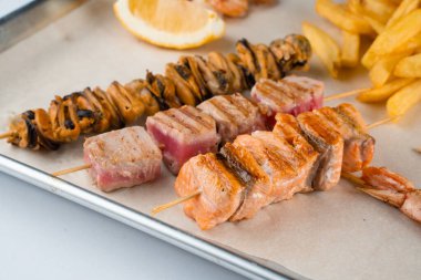 Izgara midyeli ızgara deniz ürünleri kebabı, ton balığı, ahşap şiş, beyaz sos ve limonlu somon.