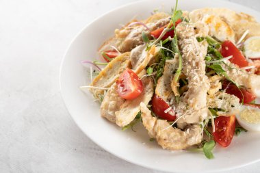 Tavuk, parmesan, vişneli domates, marul, kızarmış ekmek, beyaz tabakta yumurta..