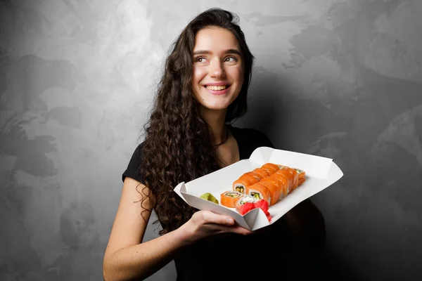 Menina Segurando Rolos Filadélfia Uma Caixa Papel Fundo Cinza Sushi — Fotografia de Stock