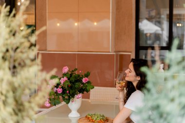 Yazlık terasta Pinsa Romana 'lı bir kız. Pinsa yiyip şarap içen genç bir kadın..