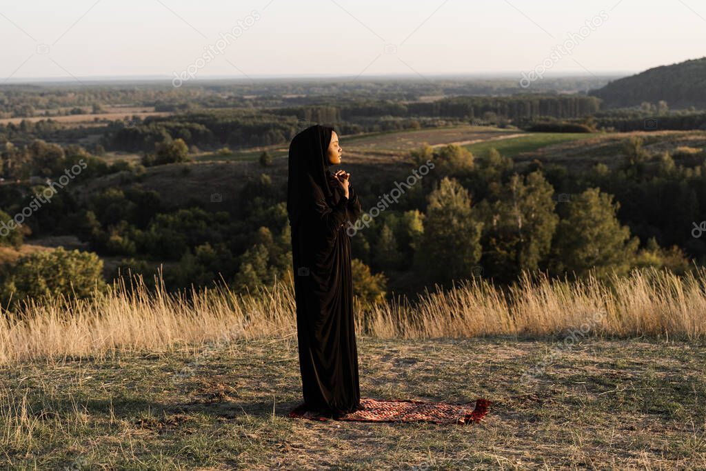 Black muslim woman praying on the carpet. Solat praying on the beautiful hill. Salah traditional pray