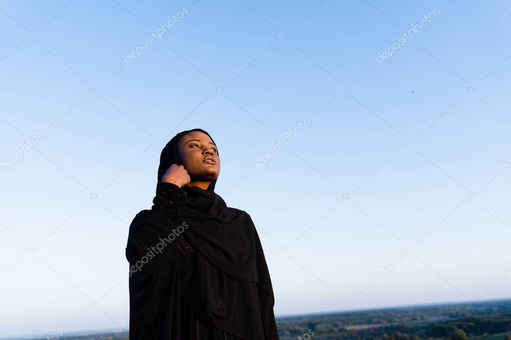 Black muslim woman weared in black robe on blue background. Islamic religion. Celebrating ramadan.