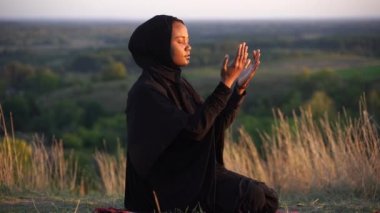 Halıda oturan siyah Müslüman kadın. Geleneksel Tanrı 'ya dua et.