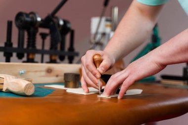 Deri işçiliği kusursuz kesim gösteriyor. Yetenekli zanaatkar deriyi doğrulukla keser. Deri kesimi desenli. Deri ustası gizlenmek için şablon kullanır