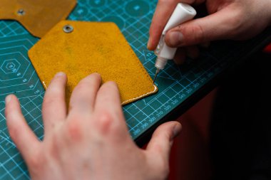 Deri kenarlara yapıştırıcı sürüyorum. Deri ürünler üretimi güçlü bir yapıştırıcıyı güvenli bir şekilde kenetleyerek başlar. Deri ustaları dikiş atmadan önce kenar hazırlamak için yapıştırıcı kullanır.