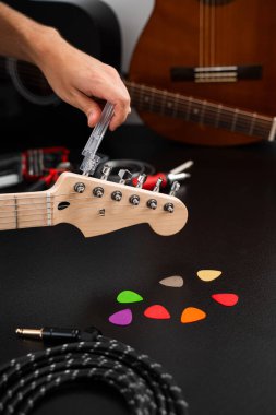 Gitar Bakım ve İp Değiştirme. Gitar başlığı bir ip cambazıyla ayarlanıyor. Gitar telleri cilalanmış bir başlık üzerinde açık plastik bir Winder ile sıkılaştırılır.