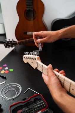Gitar telleri cilalanmış bir başlık üzerinde temiz bir plastik Winder ile sıkılaştırılır. Gitar Bakım ve İp Değiştirme. Gitar başlığı bir iple ayarlanıyor.