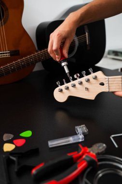 Gitar başlığı dikkatlice tornavidayla ayarlanır. Tornavida ve aletlerle Gitar Tamiri. Müzisyen gitar başlığını hassas aletlerle tamir ediyor, ayarlama mandallarını sıkılaştırıyor