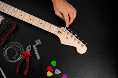 Hex Key ile Gitar Ayarlama. Gitarist köprü eyerlerini ve ip yüksekliğini ayarlamak için uğursuz anahtar kullanıyor. Gitar telleri köprüdeki uğursuz tuşla ayarlanır. Doğru tonlama ve konfor için.