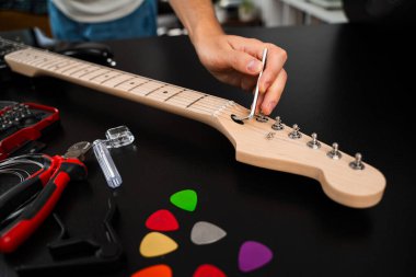 Hex Key ile Gitar Ayarlama. Gitarist köprü eyerlerini ve ip yüksekliğini ayarlamak için uğursuz anahtar kullanıyor. Gitar telleri köprüdeki uğursuz tuşla ayarlanır. Doğru tonlama ve konfor için.