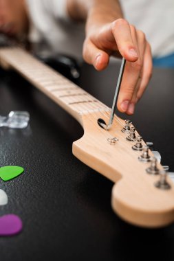 Hex Key ile Gitar Ayarlama. Gitarist köprü eyerlerini ve ip yüksekliğini ayarlamak için uğursuz anahtar kullanıyor. Gitar telleri köprüdeki uğursuz tuşla ayarlanır. Doğru tonlama ve konfor için.