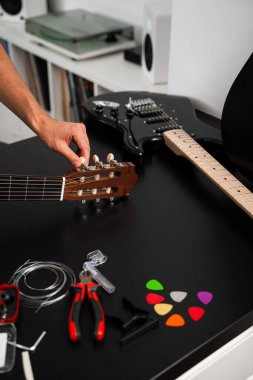 Gitar teli değiştirme ve akort hazırlığı. Müzisyen, aletleri ve yedek telleri kullanarak gitar çalar. Gitar akort süreci raptiyeleri ayarlamayı ve daha iyi ses için yeni dizgiler hazırlamayı içerir