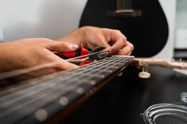 Gitarist, klasik gitar dizme işlemi sırasında yeni telleri penseyle buduyor. Gitar tellerini penseyle kesiyorum. Klasik gitar sicim değiştirme ve budama