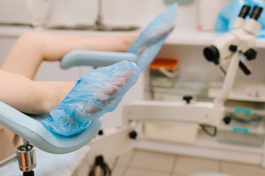 Kadın, muayeneden önce jinekoloji kürsüsünde oturuyordu. Modern jinekoloji koltuğu ve mikroskop jinekoloji sınavı için hazır. Kız, özel aletlerle jinekoloji ofisinde danışmanlık bekliyor.