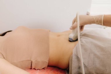 Jinekolog, sakin bir hastaya karın ultrasonu uygular. Karın ultrasonu. Jinekolog üreme sağlığı değerlendirmesi için ultrason cihazı kullanıyor.