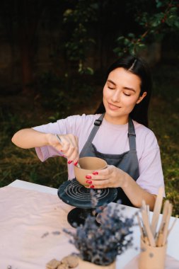 Çanak çömlek oymacılığı. Kil oyma sanatı ayrıntılı olarak gösterilir. Kil kaseleri yontma süreci yaratıcılık, işçilik ve seramik geleneklerle harmanlanır.