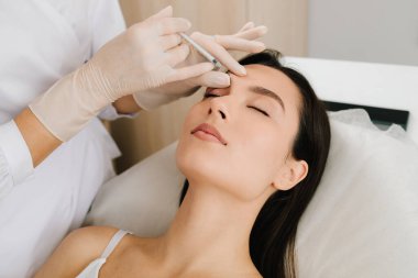 Alnın için cerrahi olmayan botulinyum toksin tedavisi. Glabellar Botulinum Toksin Enjeksiyonu. Yakın çekim. Botulinyum toksin pürüzleri kullanarak kırışıklık önleyici terapi.