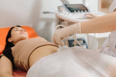 Jinekolog, sakin bir hastaya karın ultrasonu uygular. Karın ultrasonu. Jinekolog üreme sağlığı değerlendirmesi için ultrason cihazı kullanıyor.