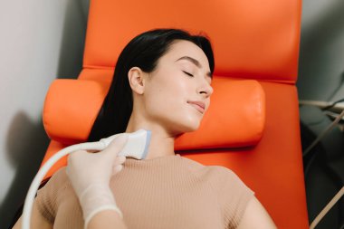 Hasta ile ultrason prosedürü. Doktor el bilgisayarı kullanarak hastaya ultrason uygular. Sonda iç yapıları çekerken kız ultrason testine tabi tutuluyor.