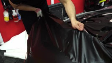 Matte siyah vinil araba kaputu boyunca uygulanır. Siyah mat vinil kullanılarak araba ambalajlama işlemi tamamlandı. 4k video uygulaması ve siyah vinil gerilimi yüzey hasarı veya kabarcıklarından kaçınır.