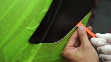 4K video kenarlı bir araç paneli etrafında mat siyah sargı uygulamak için kırpma aracı. Trim Tool 'la araba sarma. Araç temizleme, pürüzsüz bitiş için plastik takoz aracı kullanılarak budanma etrafına vinil sarma uygular.