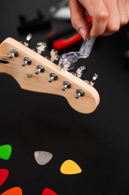 Gitar Bakım ve İp Değiştirme. Gitar başlığı bir ip cambazıyla ayarlanıyor. Gitar telleri cilalanmış bir başlık üzerinde açık plastik bir Winder ile sıkılaştırılır.