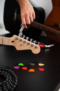 Gitar telleri cilalanmış bir başlık üzerinde temiz bir plastik Winder ile sıkılaştırılır. Gitar Bakım ve İp Değiştirme. Gitar başlığı bir iple ayarlanıyor.