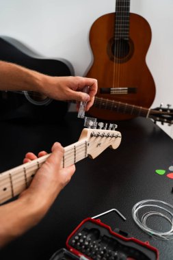 Gitar Bakım ve İp Değiştirme. Gitar başlığı bir ip cambazıyla ayarlanıyor. Gitar telleri cilalanmış bir başlık üzerinde açık plastik bir Winder ile sıkılaştırılır.