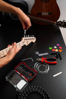 Gitar başlığı dikkatlice tornavidayla ayarlanır. Tornavida ve aletlerle Gitar Tamiri. Müzisyen gitar başlığını hassas aletlerle tamir ediyor, ayarlama mandallarını sıkılaştırıyor