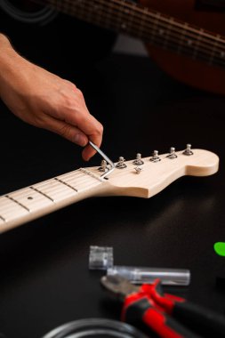 Hex Key ile Gitar Ayarlama. Gitarist köprü eyerlerini ve ip yüksekliğini ayarlamak için uğursuz anahtar kullanıyor. Gitar telleri köprüdeki uğursuz tuşla ayarlanır. Doğru tonlama ve konfor için.