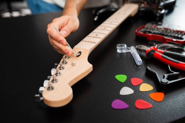 Gitar telleri köprüdeki uğursuz tuşla ayarlanır. Doğru tonlama ve konfor için. Hex Key ile Gitar Ayarlama. Gitarist köprü eyerleri ve dizgi yüksekliğini ayarlamak için bir hex anahtarı kullanır