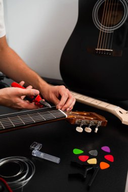 Gitarist, klasik gitar dizme işlemi sırasında yeni telleri penseyle buduyor. Gitar tellerini penseyle kesiyorum. Klasik gitar sicim değiştirme ve budama