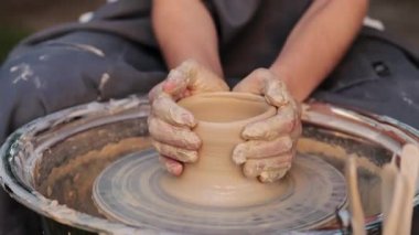 Clay dönen bir çömlek çarkında şekillenir ve seramik bir kap 4K videosunun ilk şeklini yaratır. Eller tekerlek üzerinde kilin merkezini belirliyor. Clay, şekil vermeden önce dengeyi sağlamak için bir çömlek çarkına odaklanmış..