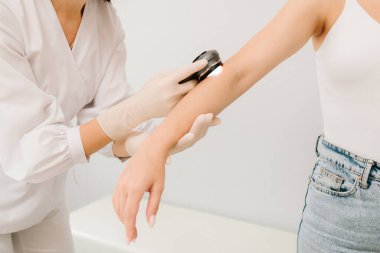 Dermatolog Dermatoskoplu Kız Cildi 'ni inceliyor. Dermatoskopik analiz klinik muayene sırasında dermatoskop kullanan şüpheli deri beneklerinin tespitine yardımcı olur.