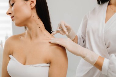 Nefertiti boynundaki işaretli noktalarla enjeksiyonu kaldırıyor. Kozmetik uzmanı kızın platizmasına botulinyum toksini enjekte edilmeden önce nokta çiziyor.