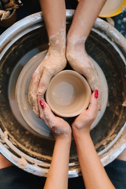 İki çift el çömlek çarkında birlikte çalışarak kilin şeklini alırlar. Çamuru pürüzsüz seramik bir kaba hassasiyetle şekillendirmeyi öğretmek