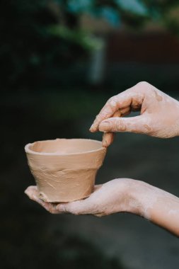 Seramik demlik sanatsallığı, sabrı ve kültürel geleneği yansıtır. Ellerindeki kil çömleği bitirdim. El yapımı kil kase direksiyondan çıkarıldıktan sonra tutulur.