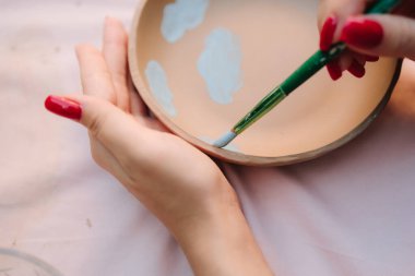 İçinde mavi çizimler olan seramik kâse. Seramik kasenin içine mavi boya çizimleri. Mavi boya tasarımlarıyla dekore edilmiş seramik kase el yapımı seramik seramiklerinin detaylı çömlek boyama sürecini gösteriyor.