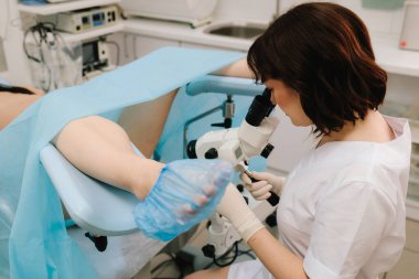 Jinekolog koloskopiyi profesyonel mikroskopla yapıyor. Hasta modern koloskopi cihazlarıyla jinekolojik muayeneden geçiyor. Jinekoloji kliniğinde koloskopi testi