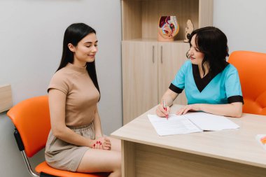 Jinekolog, üreme sistemini tıbbi konsültasyon sırasında anatomik rahim modeli kullanarak açıklıyor. Jinekolojik ziyaret kadınları doğurganlık, sağlık ve önleme konusunda eğitir