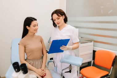 Jinekolog, Pap test sonuçlarını hastasıyla tartışıyor. Jinekolog, bir klinikte hastasıyla birlikte teşhis bulgularını inceliyor.